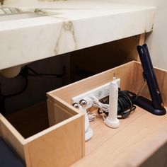 a hair dryer sitting on top of a wooden cabinet next to a sink and power strip