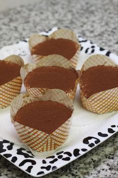 some cupcakes are sitting on a plate with paper wrappers around them and chocolate frosting in the middle