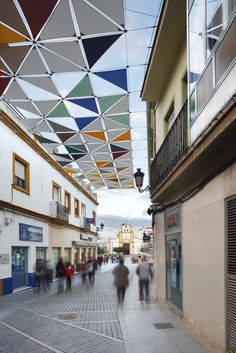 people walking down the street under colorful umbrellas