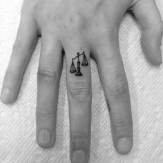 a person's finger with a tattoo on it that has a scale and an arrow