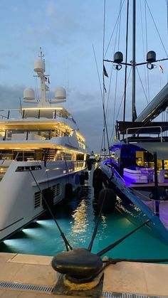 two yachts docked at a dock in the evening