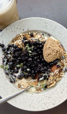 a white plate topped with blueberries and granola next to a glass of milk