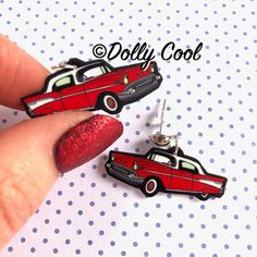 a pair of red and black cars are being held by a woman's finger