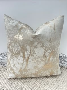 a white and gold pillow sitting on top of a bed