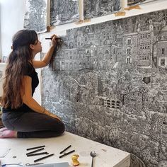 a woman sitting on top of a table writing on a wall