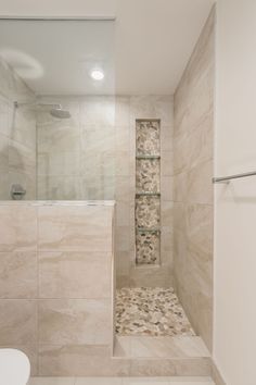 a bathroom with a walk in shower next to a white toilet and tiled flooring