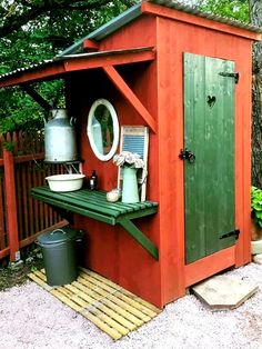 a red shed with a green door and shelves on the outside, next to a tree