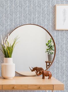 a mirror sitting on top of a wooden table next to a potted plant and toy rhino