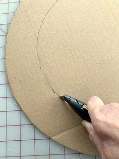 a person is cutting out a piece of cardboard with a sharpie pen and scissors