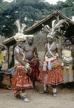 some people are standing in front of a hut