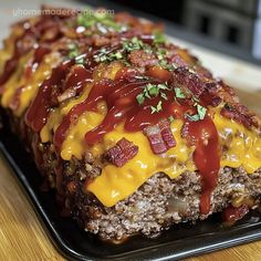 meatloaf with cheese and bacon on a black plate sitting on a wooden table