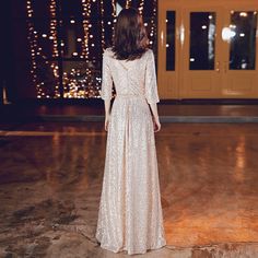 a woman in a long white dress standing on a dance floor with lights behind her