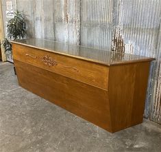 a wooden bench sitting in front of a metal wall with a potted plant next to it