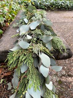 a bunch of green leaves and greenery on a stone bench