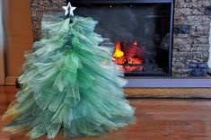 a green christmas tree sitting on top of a wooden floor next to a fire place