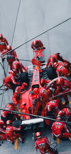 a group of mechanics working on a race car in the pit area, from above