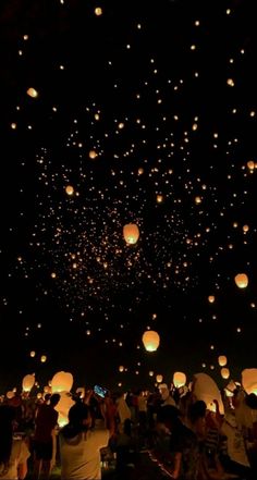 many people are flying lanterns in the night sky with bright lights on them and there is no image here to provide a caption for