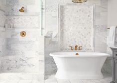 a white bath tub sitting next to a toilet in a bathroom under a chandelier