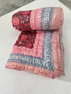 two red and blue patterned bedspreads on top of a white bed coverlet