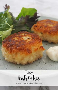 two crab cakes on a plate with lettuce and mayonnaise next to it