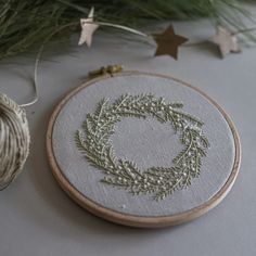 an embroidered wreath sits on a table next to some twine spools