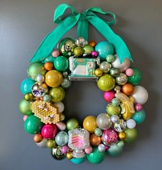 a christmas wreath hanging on the wall with ornaments around it and a camera in the middle