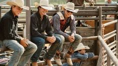 three men and two women are sitting on the back of a fence in cowboy hats