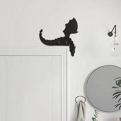 a white room with a mirror, plant and clock on the wall next to it