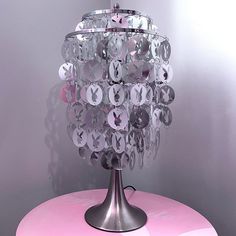 a pink table topped with a crystal chandelier on top of a metal stand