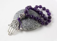 A deep purple Amethyst mini mala will easily fit into a pocket/purse/yoga bag. The perfect tool for stress relief! You don't have to be into meditation to appreciate the soothing feel of this polished natural stone in your hand. Perfect for keeping with you all day long or at your bedside for a few moments of quiet retreat, meditation or affirmation practice. SIZE/LENGTH: Silver healing hand pendant measures approx. 35mm (1 3/8 inches); The beaded portion of this small pocket mala measures appro Bohemian Purple Polished Beads, Spiritual Purple Spacer Beads, Hand-strung Purple Bohemian Beads, Purple Hand-strung Bohemian Beads, Bohemian Hand-strung Purple Beads, Purple Bohemian Hand-strung Beads, Purple Round Beads Bracelet For Meditation, Purple Beaded Bracelets For Meditation, Spiritual Purple Beaded Necklaces For Gifts