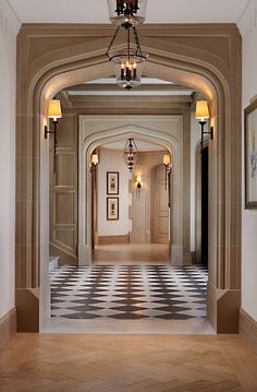 the hallway is decorated in beige and black checkerboard flooring, along with two chandeliers