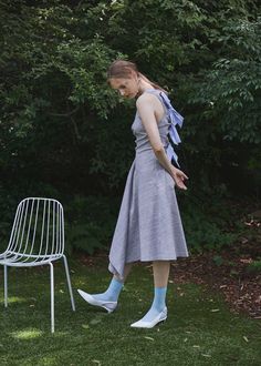 a woman standing in the grass next to a chair