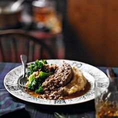 a plate with mashed potatoes, broccoli and meat in gravy