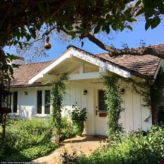 a white house surrounded by greenery and flowers