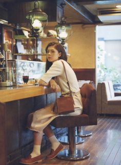 a woman sitting at a bar with a brown purse