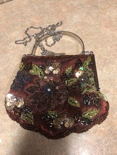 Gorgeous rust color small formal purse. The outside has beads and sequence on it designed as flowers. There is a small silver oval metal handle and also a chain in order to utilize the handbag as a crossbody.  6 x 5 1/4 inches Brown Crossbody Evening Bag For Parties, Vintage Brown Evening Bag For Party, Brown Embellished Evening Bag, Handmade Victorian Style Silver Bags, Vintage Handmade Silver Bag, Vintage Silver Embellished Evening Bag, Formal Purse, Vintage Pink Beaded Bag, Antique Beaded Purse