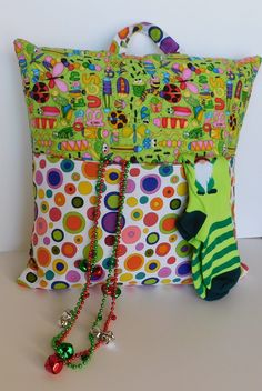 a colorful pillow and some accessories on a white table with a green polka dot bag