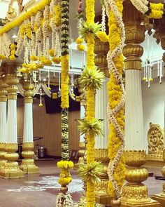 the interior of a building decorated with yellow flowers and garlands on columns, chandeliers and pillars