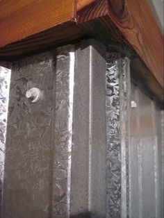 the corner of a wooden shelf with metal foil covering it and wood trimmings