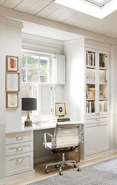 a home office with white cabinets and drawers