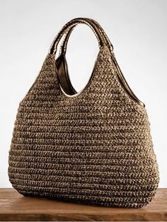 a brown handbag sitting on top of a wooden table next to a white wall