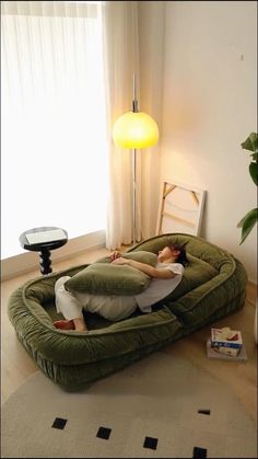 a large green couch sitting on top of a floor next to a table with a lamp