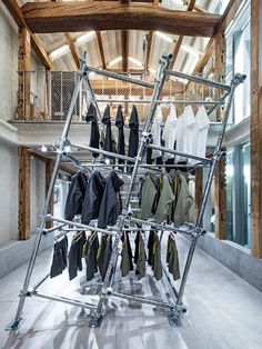 clothes are hanging on a metal rack in the middle of a room with exposed ceilings