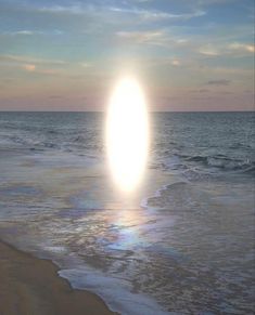 the sun is setting over the ocean with waves crashing on the beach and an object in the air