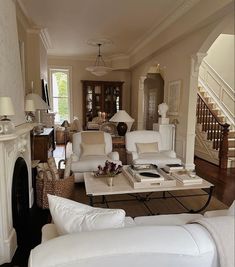 a living room filled with white furniture and a fire place in front of a fireplace