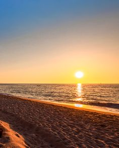 the sun is setting over the ocean on the beach