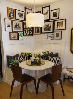 a dining room table with chairs and pictures on the wall above it in a home