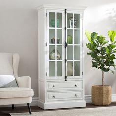 a living room with a chair and a white china cabinet