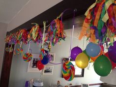 balloons and streamers hanging from the ceiling in a room with pictures on the wall