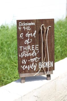 a wooden sign with writing on it sitting in front of some green grass and the words,